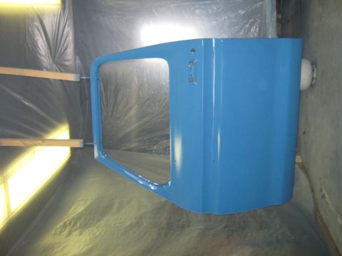 1977 Ford F-150 - A blue truck door is being prepped for painting in a spray booth.