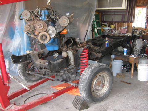 1977 Ford F-150 - Vehicle chassis and engine undergoing work in a garage setting.