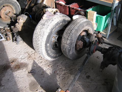 1977 Ford F-150 - Vehicle axles and tires are stored indoors, possibly for repair or replacement.