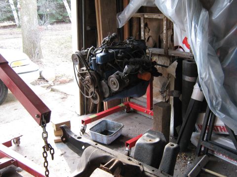 1977 Ford F-150 - An engine is mounted on a stand in a cluttered garage environment.