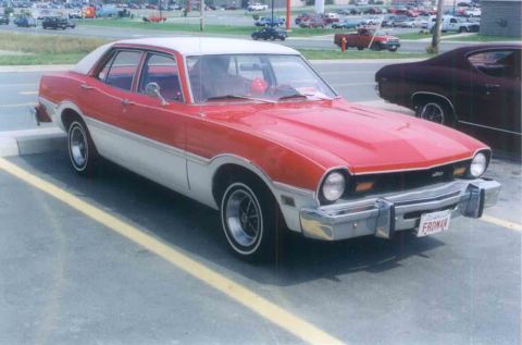 1999 Ford Crown Victoria - A red and white sedan is parked in a lot, with another dark-colored vehicle to its right.