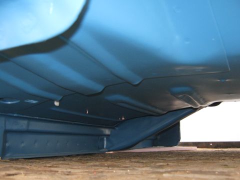 1977 Ford F-150 - The underside of a blue 1977 Ford F-150 reveals its frame and floor pan construction, with visible Supermotors.net branding.
