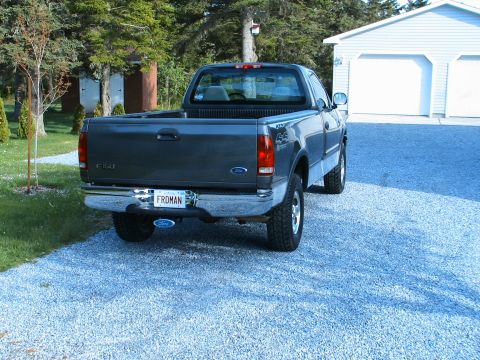 1999 Ford Crown Victoria - Dark gray 1999 Ford F-150 pickup truck with a "FRDMAN" license plate is parked in front of a garage.