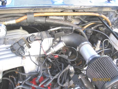 1994 Ford Bronco - Close-up view of an engine bay, showing an aftermarket air intake system and various engine components.