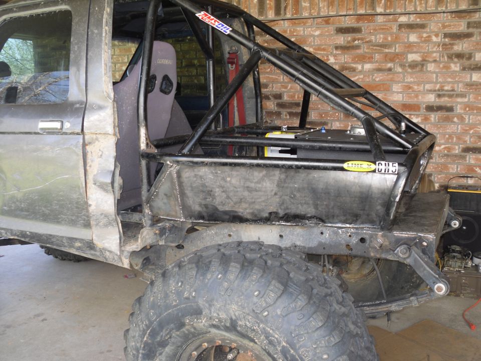 Modified off-road vehicle, dark gray, side view, showing custom roll cage, racing seat, and large tires