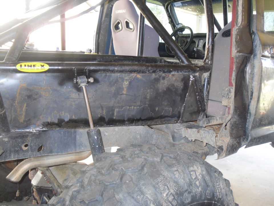 Interior view of off-road vehicle with roll cage, racing seat, and "LINE-X" sticker