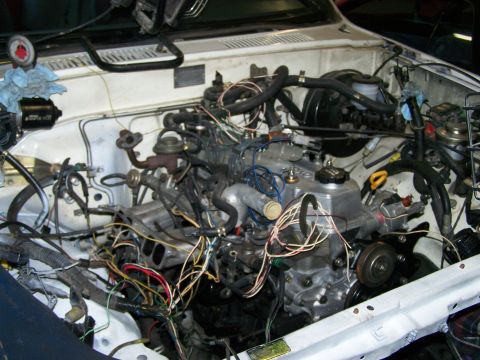 1988 Suzuki Samurai - The engine bay is filled with a complex network of wires and hoses, suggesting recent work or modifications.