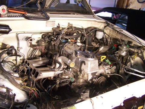 1988 Suzuki Samurai - Engine bay of a white vehicle, showing intricate wiring and engine parts.