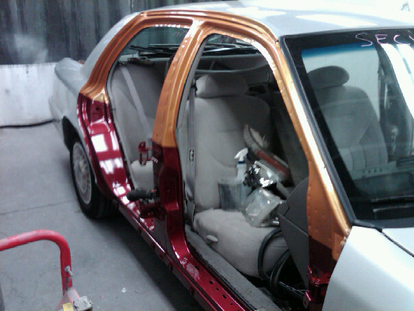 Sedan in paint booth with doors off, lower body painted candy red and copper over silver, tan interior exposed