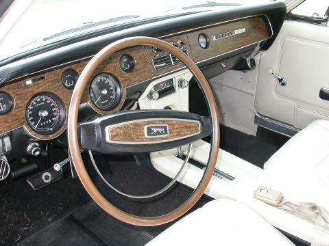 1968 Mercury Cougar - The dashboard of a 1968 Mercury Cougar features wood-grain trim and a prominent cougar emblem on the steering wheel.