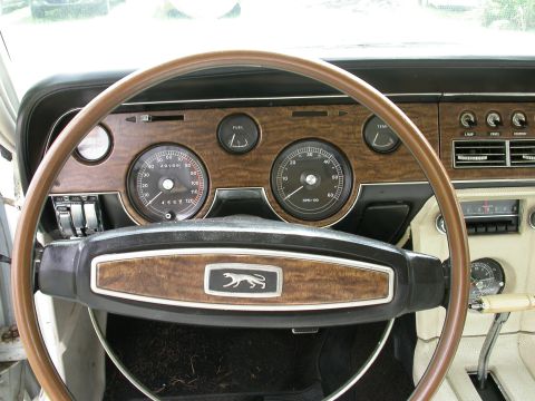 1968 Mercury Cougar - The interior of a 1968 Mercury Cougar shows its dashboard with woodgrain accents and a cougar emblem on the steering wheel.