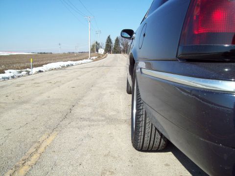 1999 Mercury Grand Marquis - Rear view of a black 1999 Mercury Grand Marquis on a country road with snow on the side.
