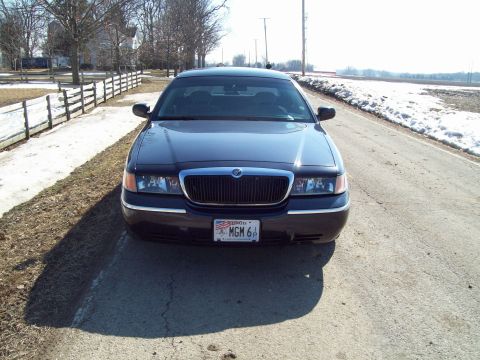 1999 Mercury Grand Marquis - A dark sedan is parked on the side of a road with snow on the ground.