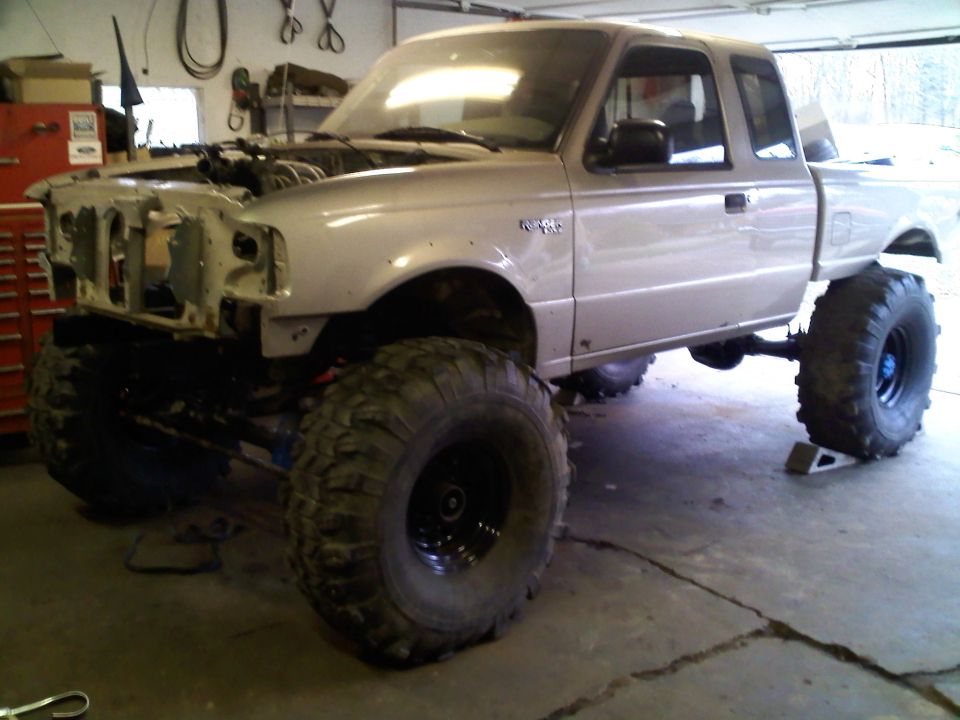 Silver 1997 Ford Ranger with massive off-road tires and lifted suspension