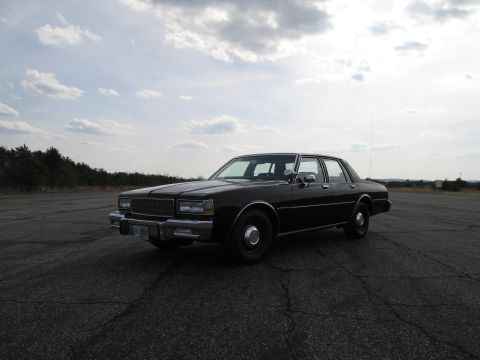 1991 Ford Crown Victoria LTD - This black sedan is parked on an asphalt lot under a cloudy sky. The vehicle's body style suggests an older model.