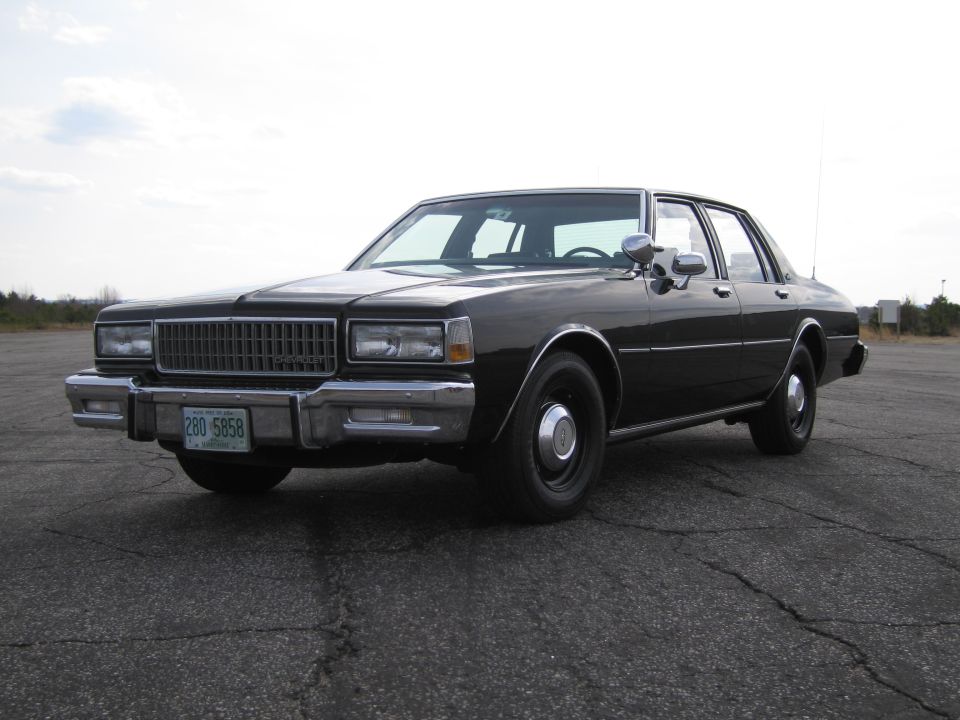 1980s Chevrolet Caprice sedan, black, parked on asphalt lot