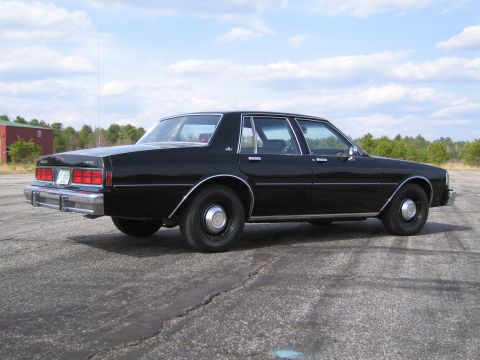 1991 Ford LTD Crown Victoria - Rear view of a black sedan, possibly from the 1980s, parked outdoors on a paved surface.