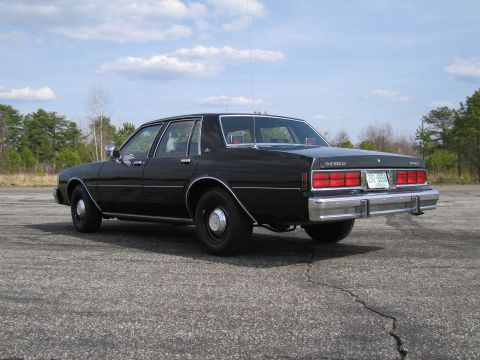 1991 Ford LTD Crown Victoria - Rear 3/4 view of a black sedan, possibly a Chevrolet Caprice, from the early 1980s.
