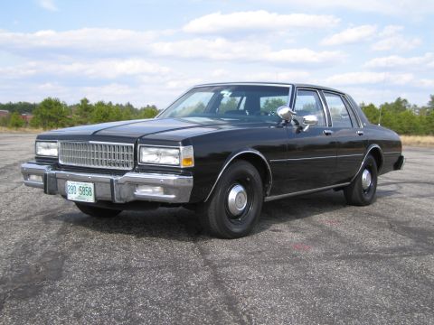 1991 Ford LTD Crown Victoria - This black Chevrolet Caprice sedan is shown from a three-quarter front view on a cloudy day.