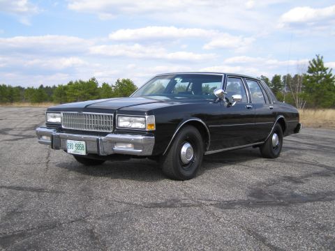 1991 Ford LTD Crown Victoria - This black sedan features a prominent chrome grille and bumper, typical of 1980s American sedans.
