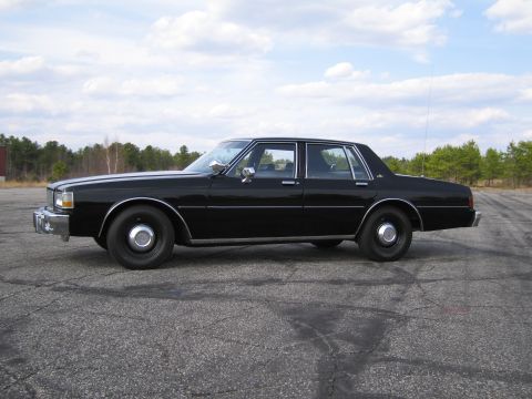 1991 Ford LTD Crown Victoria - This black sedan, likely from the early 1980s, is parked outdoors on a paved surface.