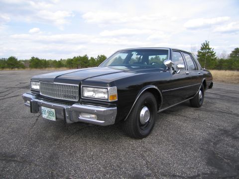 1991 Ford LTD Crown Victoria - This sedan features a prominent chrome grille and a clean exterior under a partly cloudy sky.