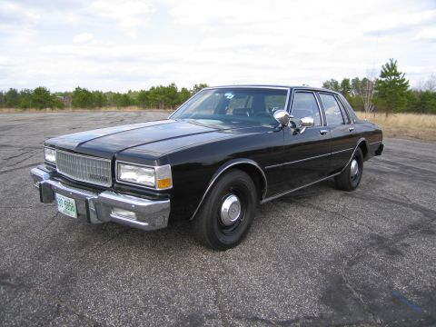 1991 Ford LTD Crown Victoria - This black sedan, likely from the 1980s, is shown from a three-quarter front angle.