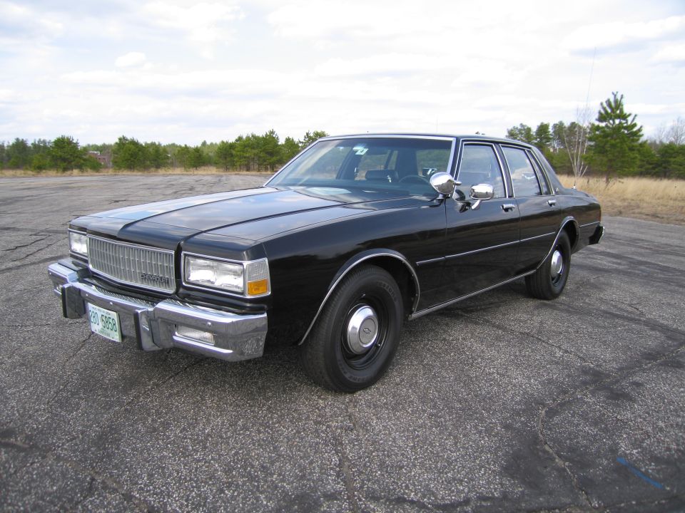 Black sedan with chrome grille and bumpers parked on asphalt