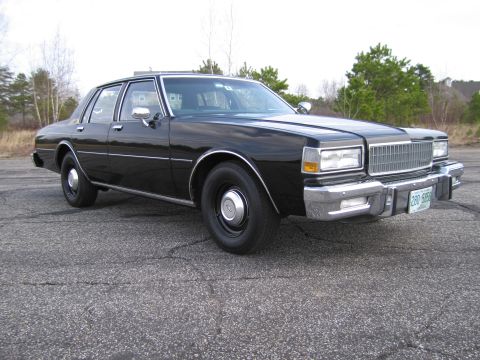 1991 Ford LTD Crown Victoria - This 1980s sedan features a prominent chrome grille and bumper, parked outdoors on a paved surface.