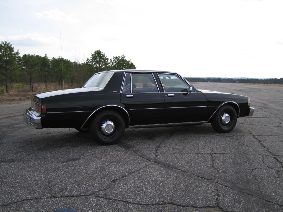 Black sedan, side view, parked on asphalt