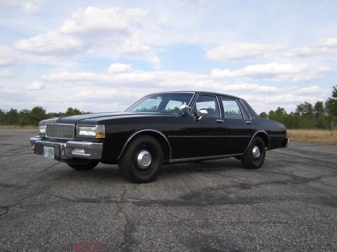 1991 Ford LTD Crown Victoria - This black sedan features a prominent chrome grille and bumper, with a clear view from the front three-quarter angle.