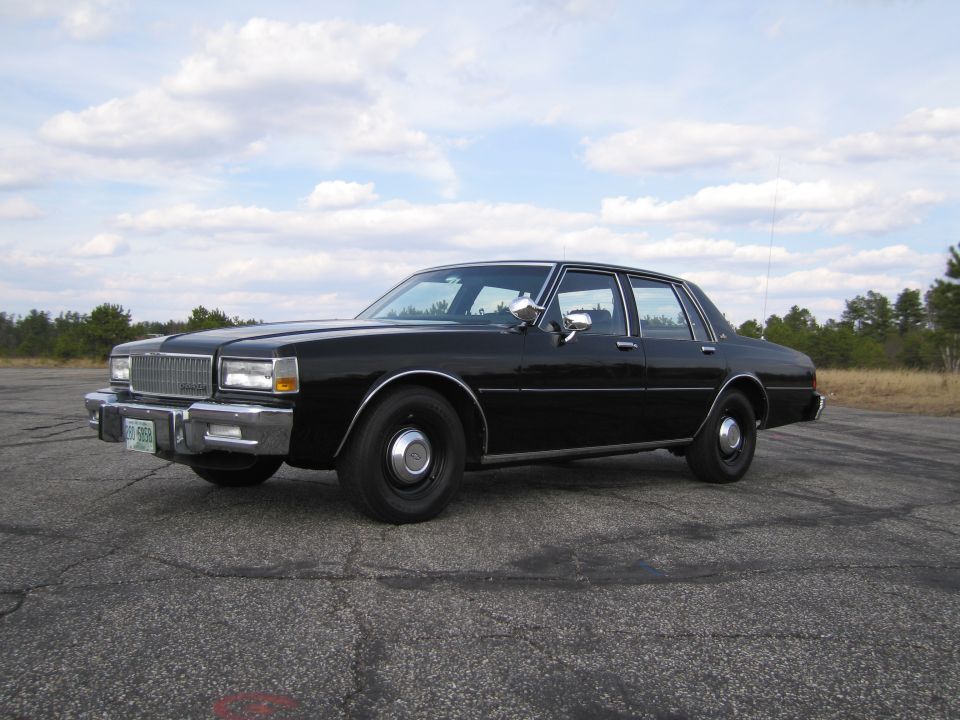 Black sedan with chrome grille and bumper, seen from 3/4 front