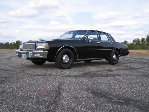 1991 Ford LTD Crown Victoria - Black sedan parked on asphalt with a cloudy sky overhead. The vehicle's body style suggests an earlier model year than claimed.