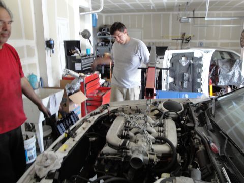 1989 Ford Taurus - Mechanics work on a car engine in a garage setting.