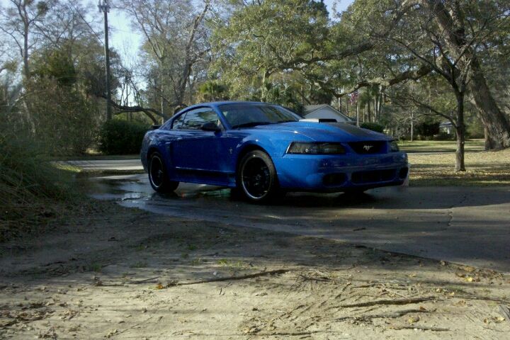 Blue coupe with black wheels and a hood scoop, angled from the front-right