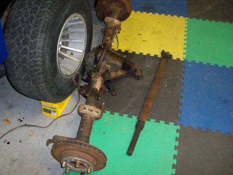 1978 Jeep CJ5 - A disassembled vehicle axle and driveshaft are shown, with a tire resting on a yellow chock.