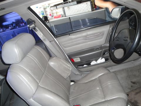 1989 Ford Taurus - The interior of a car shows gray leather seats and a dashboard with a steering wheel.