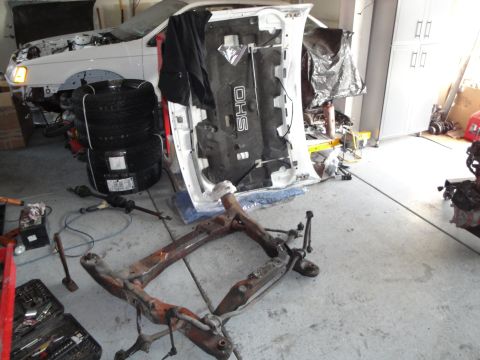 1989 Ford Taurus - Vehicle disassembled in garage, parts laid out for repair or swap.