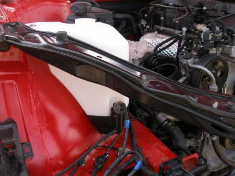 2010 Hyundai Genesis - Close-up view of a car's engine bay, focusing on the coolant reservoir and surrounding mechanical parts.
