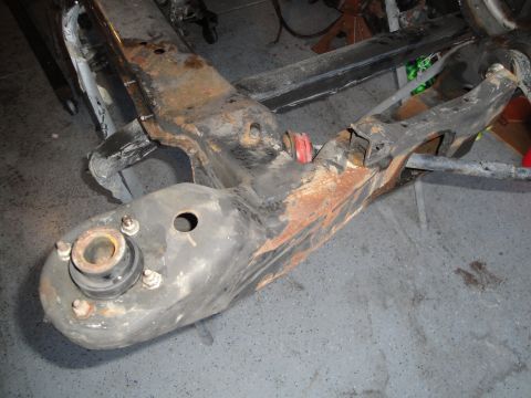 1989 Ford Taurus - Close-up of a heavily rusted vehicle subframe assembly with visible red bushings.