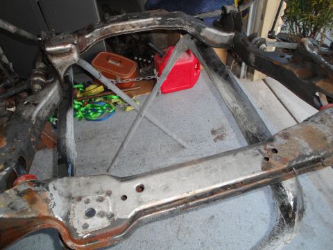 1989 Ford Taurus - A disassembled vehicle frame sits on a concrete floor, with a red gas can and orange toolbox nearby.