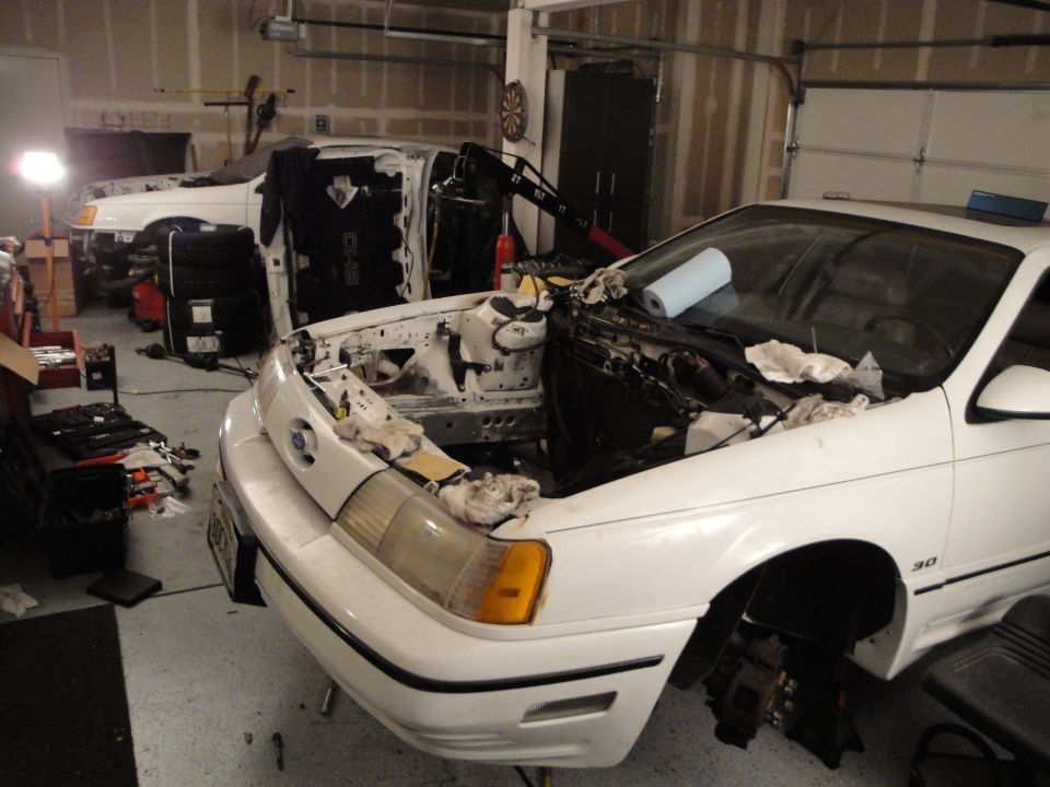 White 1989 Ford Taurus with hood open, engine bay exposed, in a garage