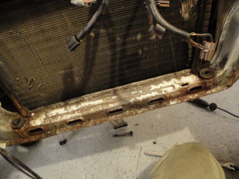 1989 Ford Taurus - Close-up of a vehicle's radiator and its mounting frame, showing signs of wear and rust.