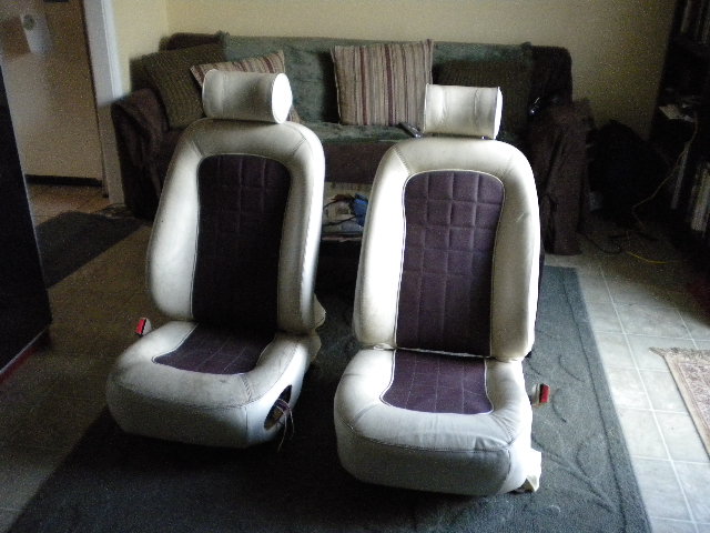 Two car seats with beige and purple upholstery, viewed from the front