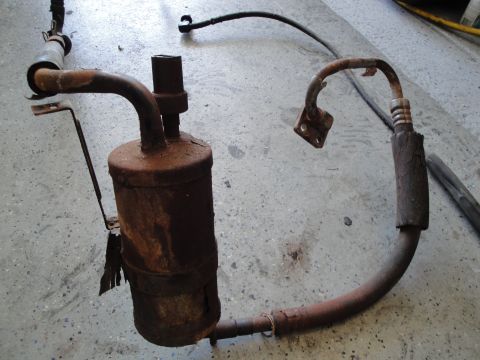 1989 Ford Taurus - This is a rusty air conditioning receiver-drier assembly with hoses and a bracket.