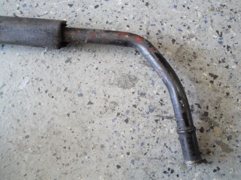 1989 Ford Taurus - A close-up view of a bent metal exhaust pipe with signs of wear and tear.