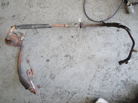 1989 Ford Taurus - This exhaust pipe assembly, likely from a vehicle, is laid out on a concrete surface.