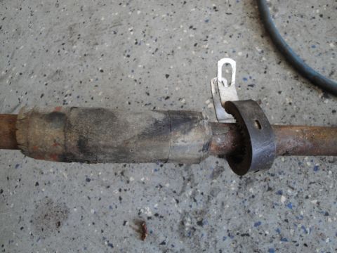 1989 Ford Taurus - Close-up of a repaired exhaust pipe section, showing a wrap and a metal clamp, resting on a concrete surface.