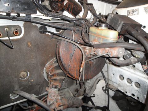 1989 Ford Taurus - Close-up of a vehicle's engine bay, focusing on the brake booster and master cylinder components.