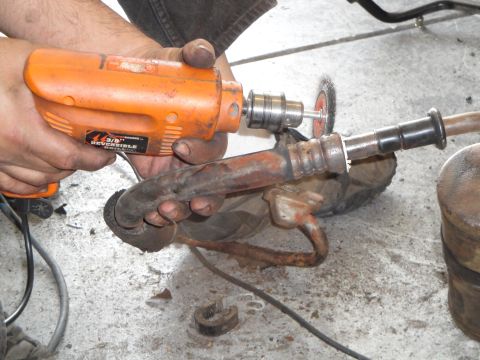 1989 Ford Taurus - Cleaning a rusty metal pipe with a drill and wire brush attachment.